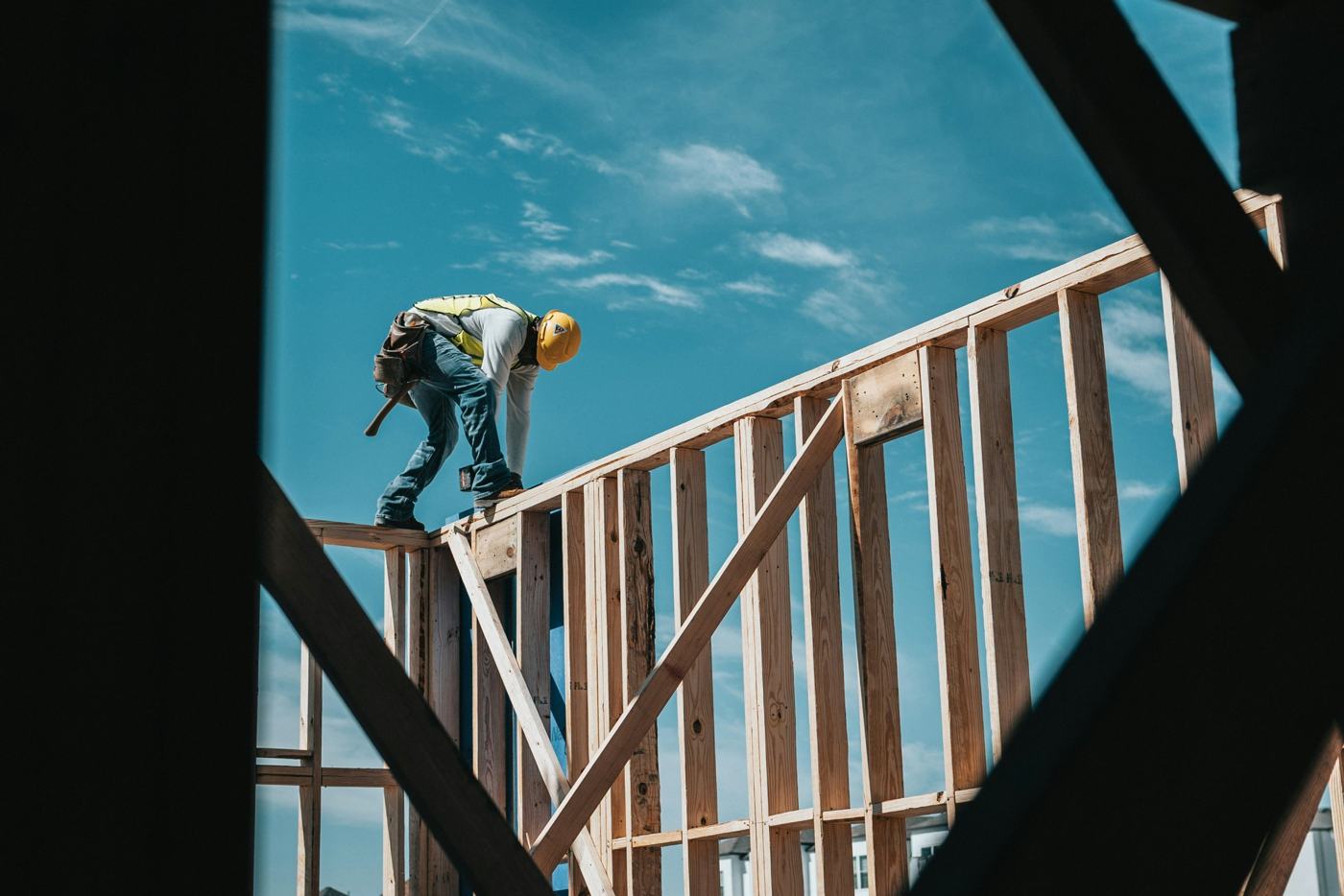 Builder framing a home against a blue sky
